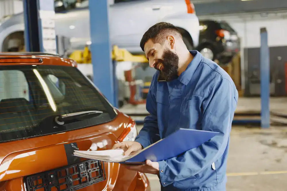 Technician reviewing a service schedule near a vehicle